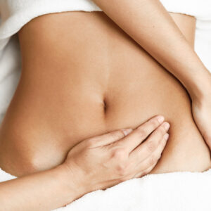 Top view of hands massaging female abdomen.Therapist applying pressure on belly. Woman receiving massage at spa salon